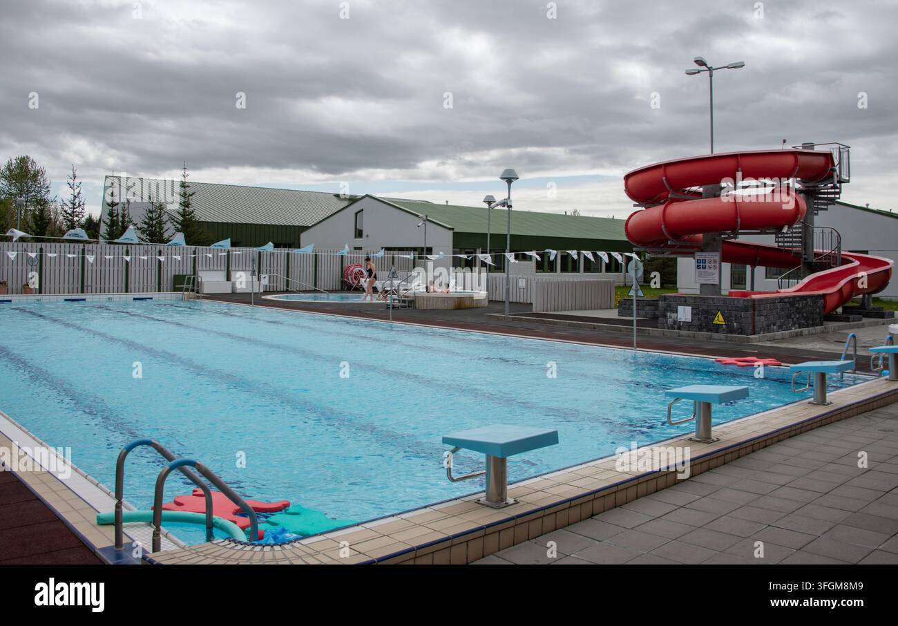 La piscina all'aperto di 25 metri di Hvolsvöllur, idromassaggi e scivolo d'acqua rosso, tipici delle piscine pubbliche delle piccole città in tutta l'Islanda. Foto Stock