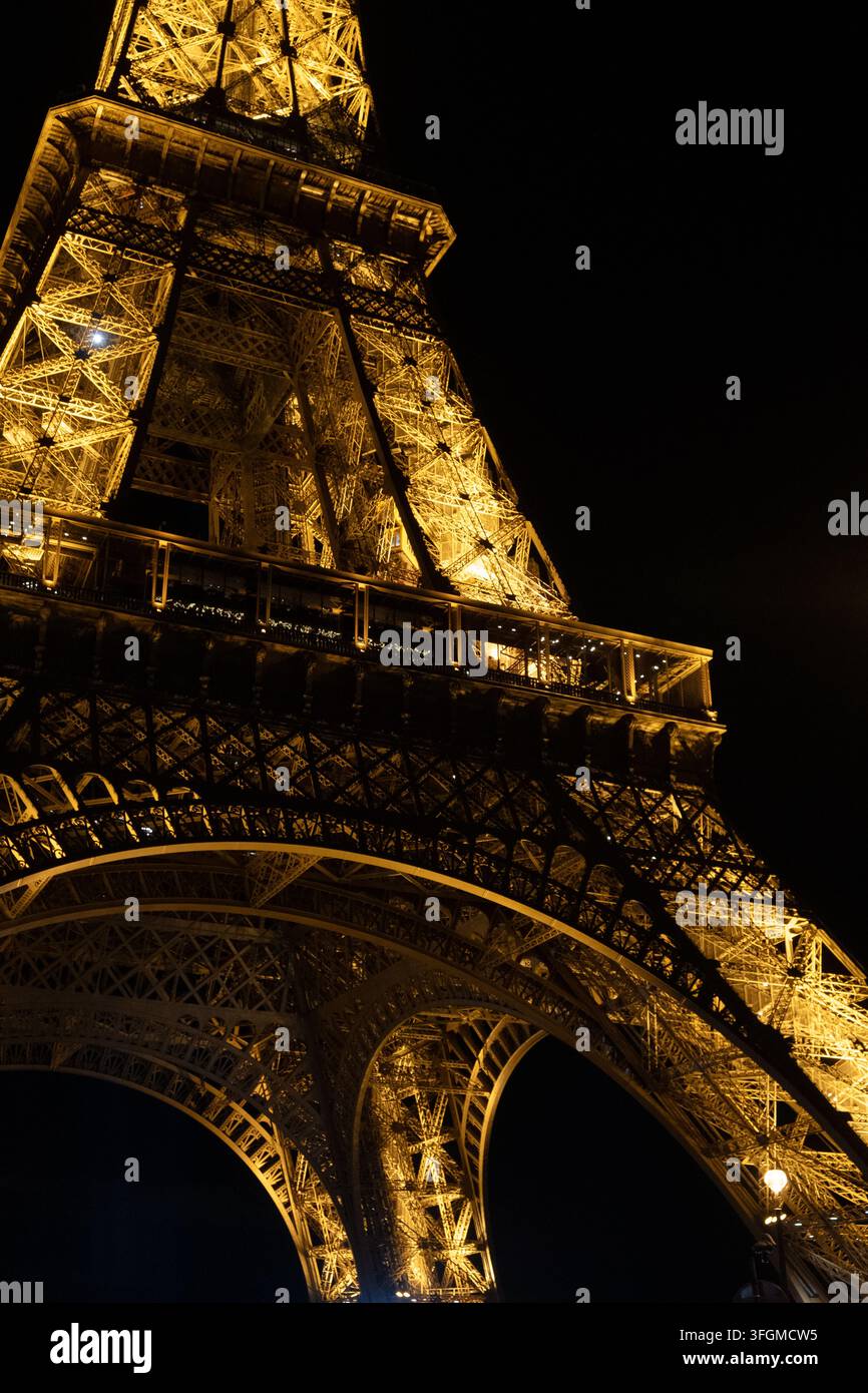 Torre Eiffel illuminata di notte vista dal basso contro un cielo nero a Parigi, Francia Foto Stock