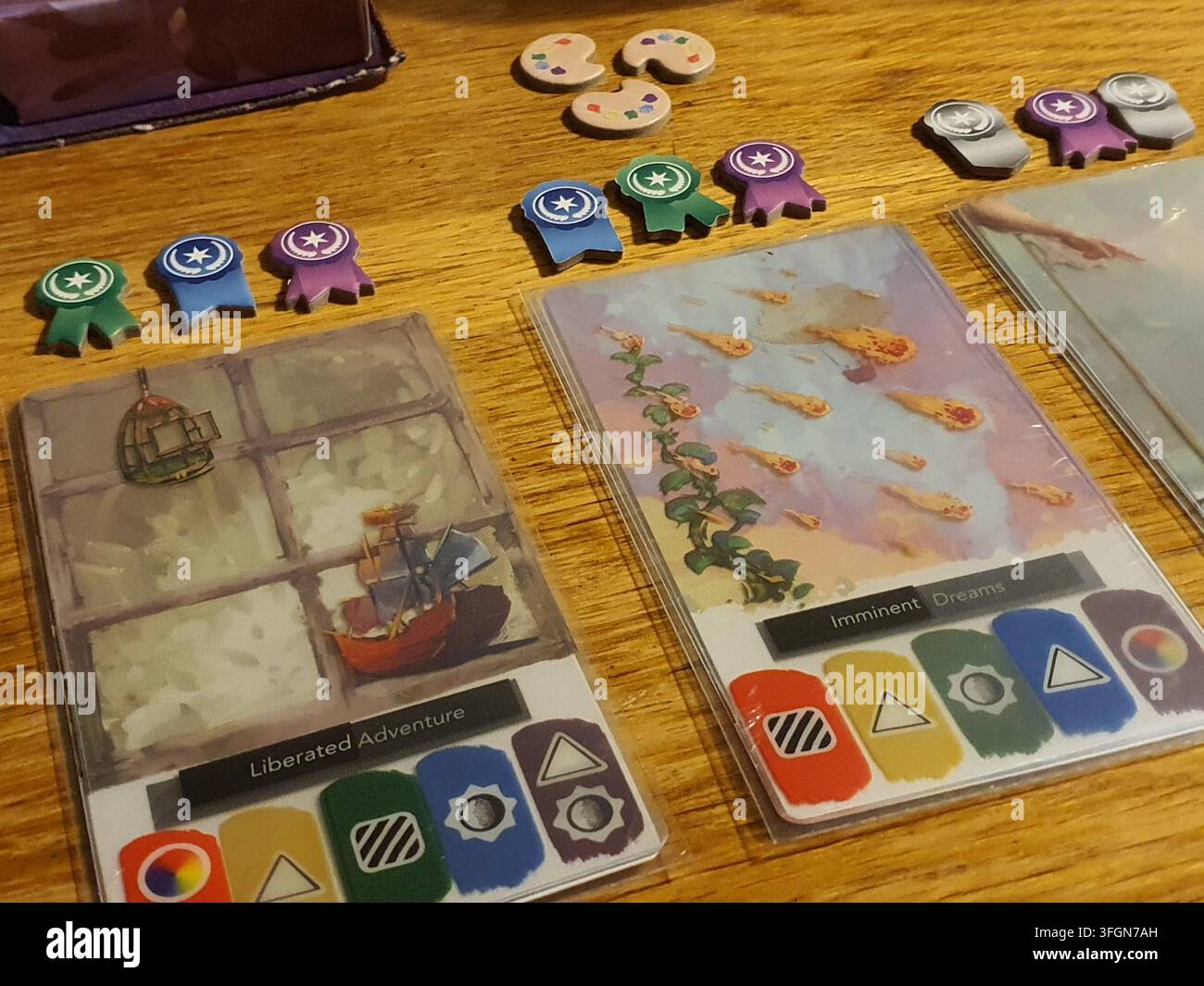 Una fotografia ravvicinata di una configurazione di gioco da tavolo con componenti del gioco "Canvas" su una superficie di legno. Due grandi carte rivestite sono Foto Stock
