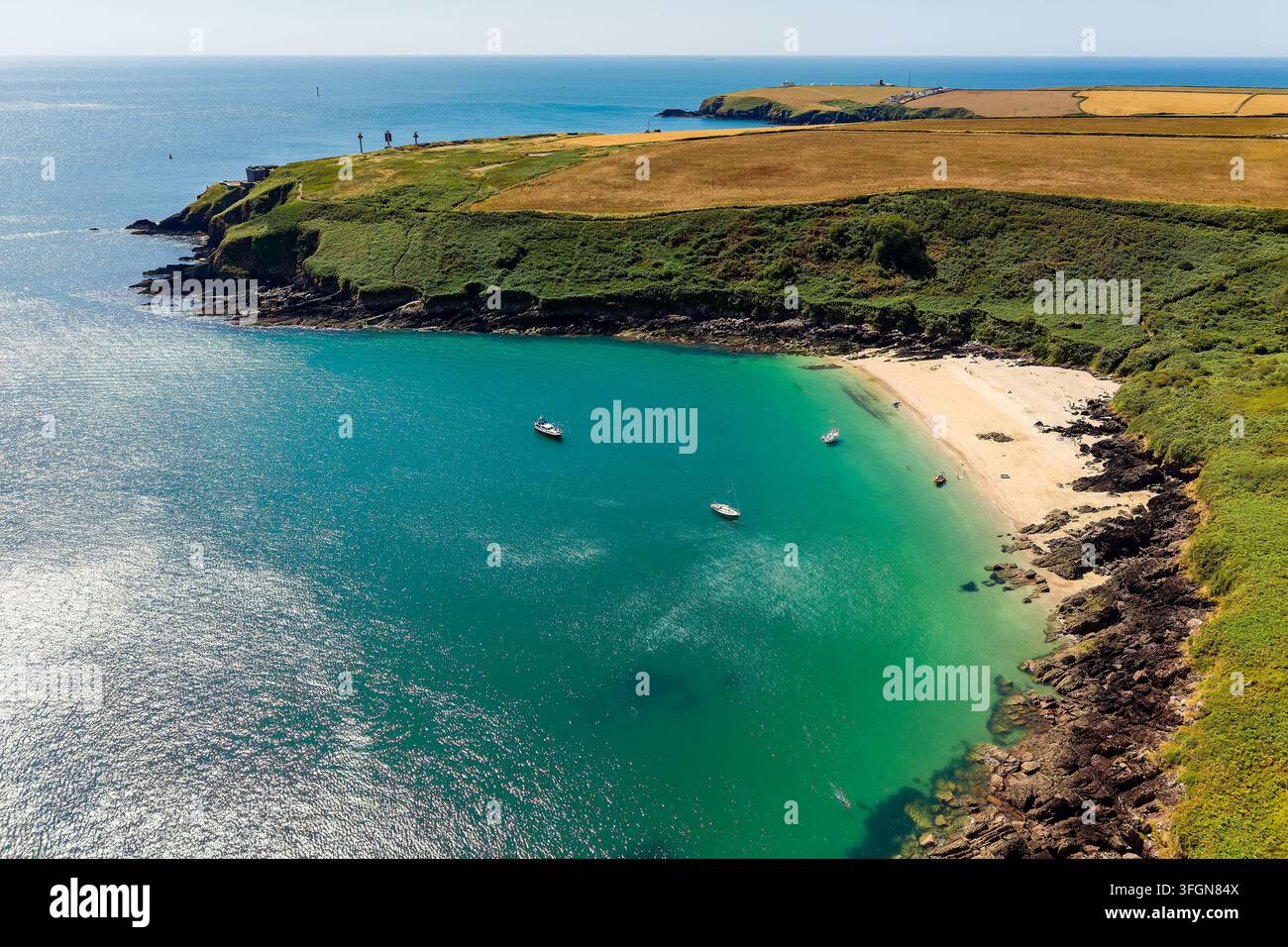 Vista aerea ad angolo alto di Watwick Bay nel Pembrokeshire, piccole barche ancorate al largo di una spiaggia sabbiosa circondata da scogliere costiere e campi verdi, Galles occidentale Foto Stock