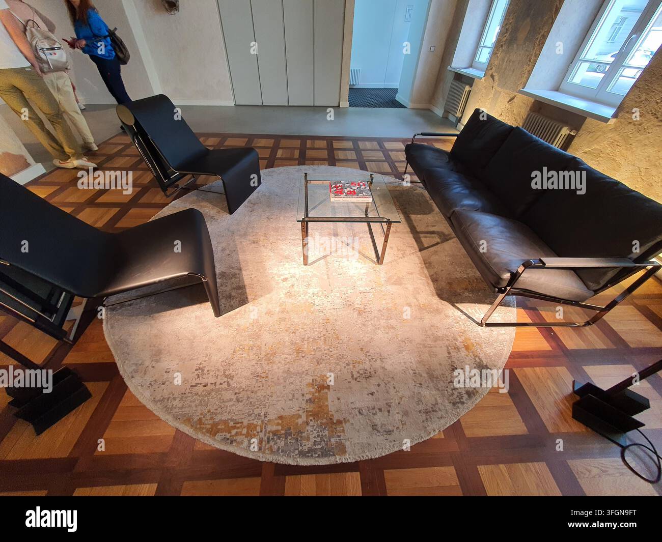 Un interno di soggiorno modernista con iconici mobili in pelle nera e strutture tubolari cromate, tra cui due poltrone lounge e un divano disposti Foto Stock