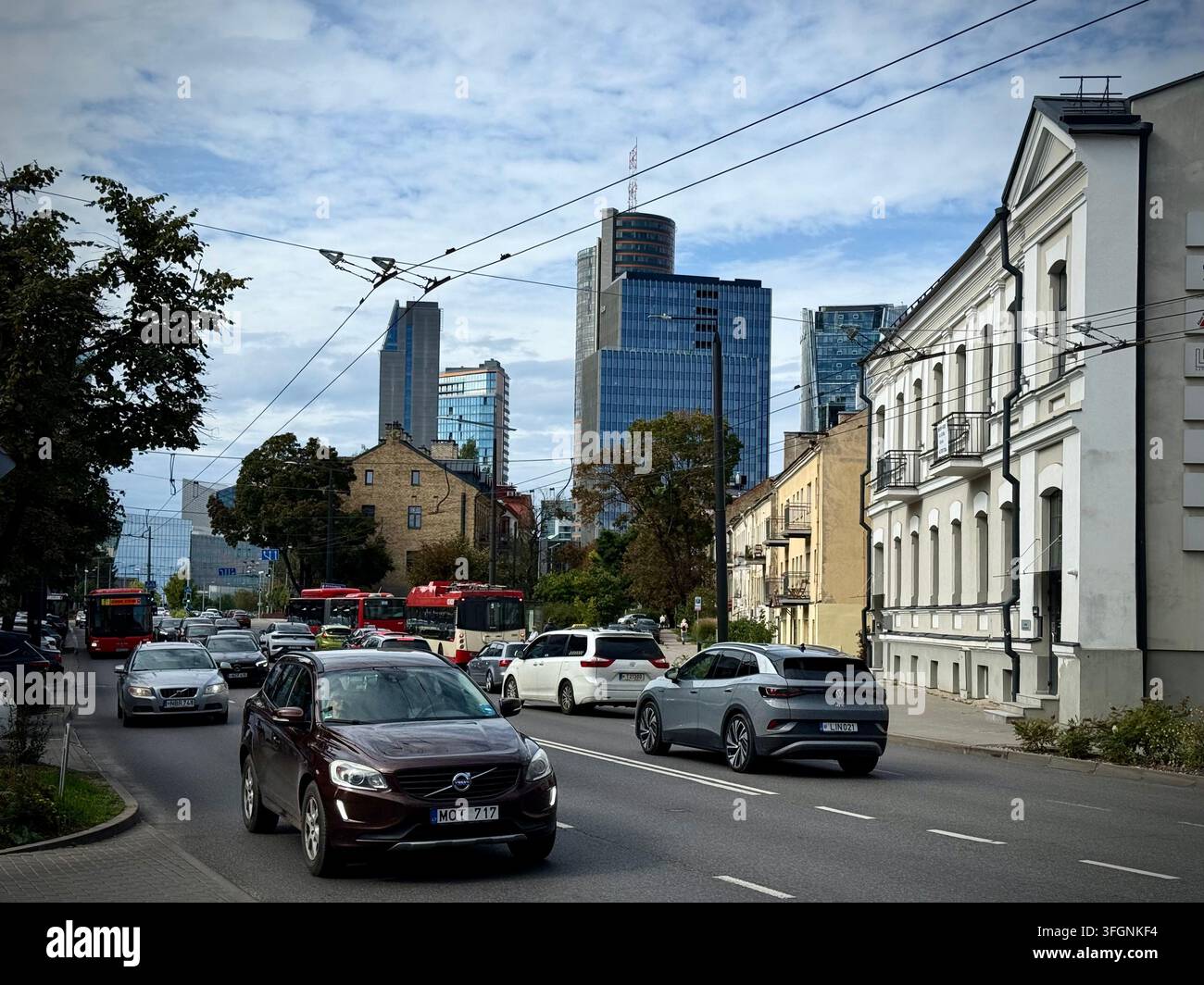 Vista orizzontale del traffico cittadino attivo lungo una strada di Vilnius con architettura storica e grattacieli moderni sullo sfondo. - Immagine stock catturata con smartphone
