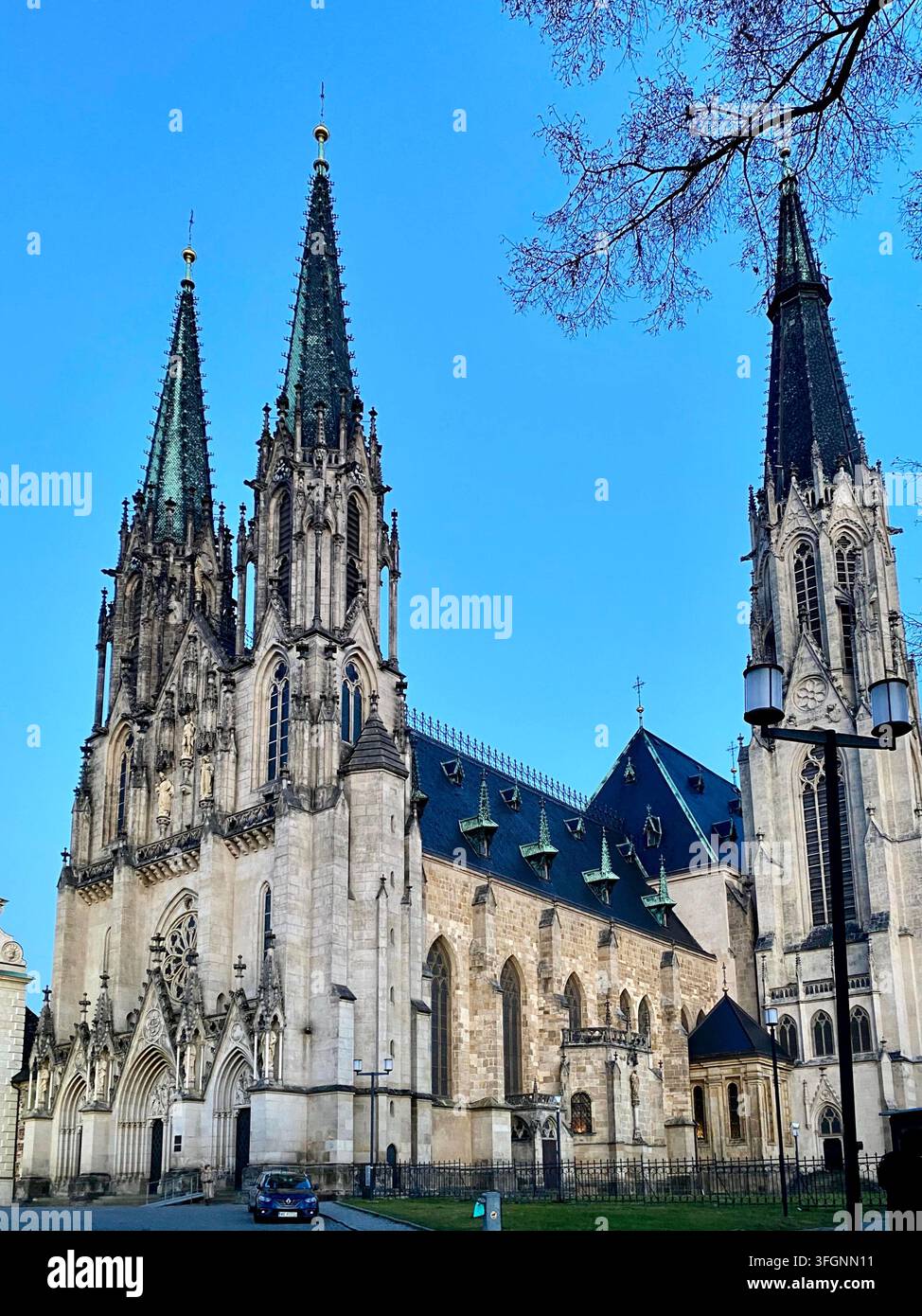 Vista verticale della Cattedrale di San Venceslao a Olomouc con due campanili neogotici gemelli, dettagli in pietra ornati e un cielo blu chiaro. - Immagine stock catturata con smartphone