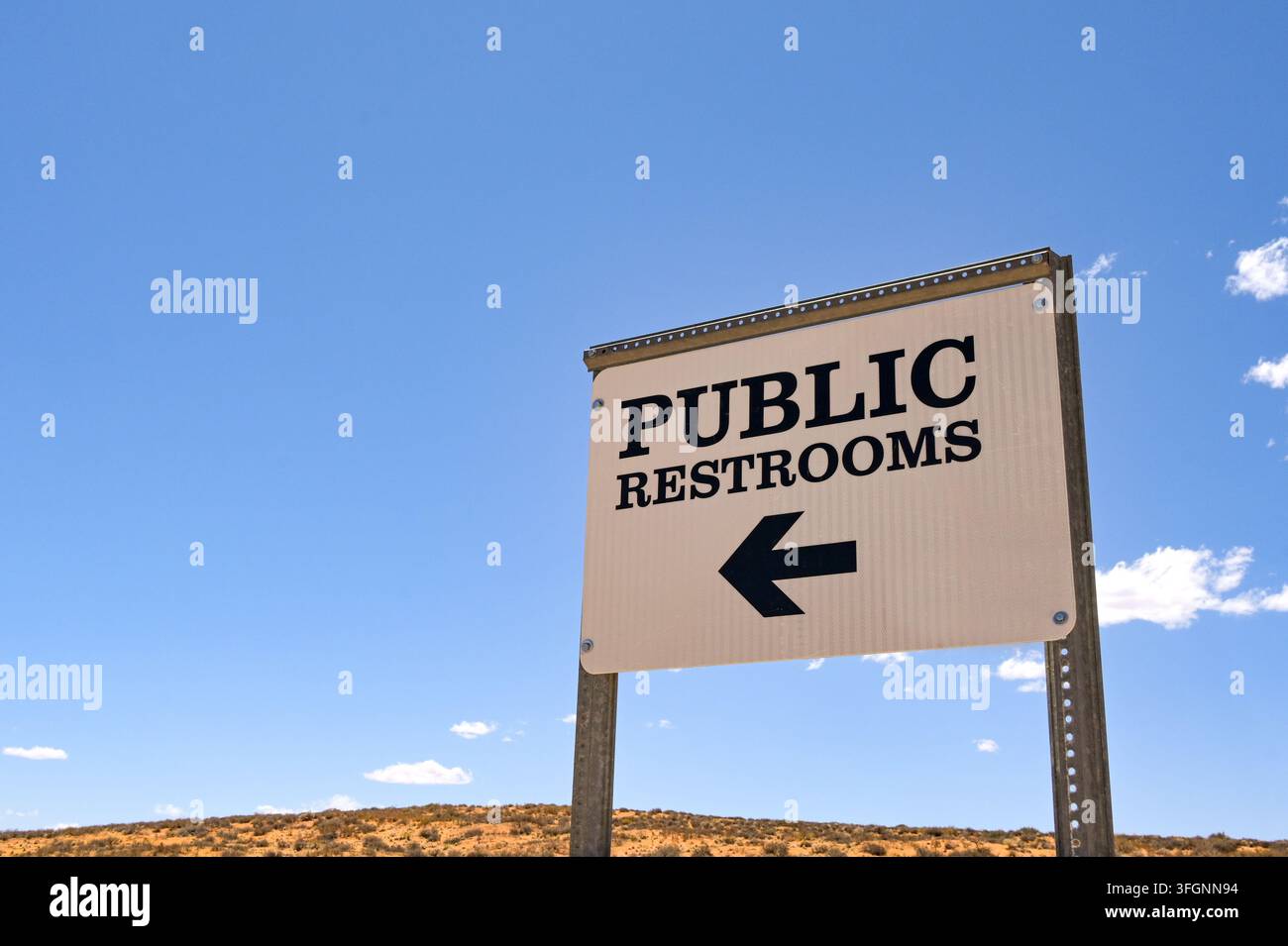 Segnale per i servizi igienici pubblici in un parcheggio isolato contro un cielo blu. Foto Stock