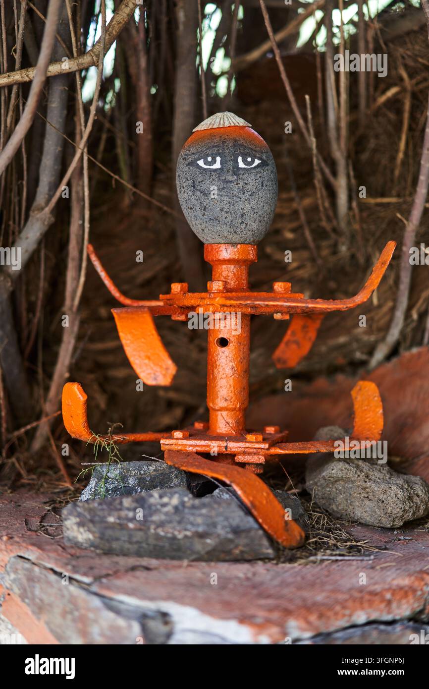 Una figura rustica di arte popolare stravagante realizzata con pezzi di metallo di scarto dipinti e una testa di pietra scolpita a Chamorga Tenerife Foto Stock