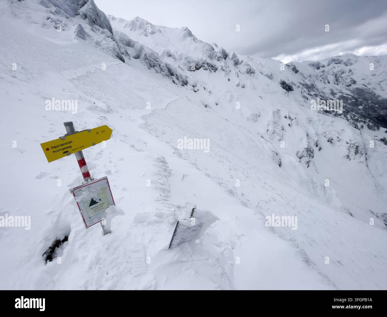 Segnale stradale direzionale giallo con cartello di avviso di valanga su un pendio montuoso ripido coperto di neve lungo il percorso di arrampicata Reichenstein nell'Eisenerzer Alp Foto Stock