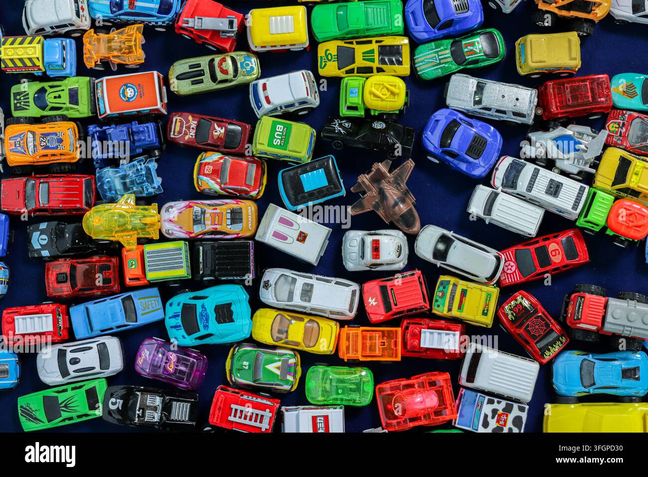 Auto giocattolo vintage da collezione e veicoli in miniatura disposti su un tessuto blu scuro al mercato di Chatuchak, Bangkok, Thailandia. Foto Stock