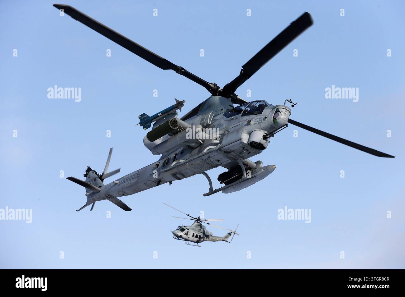 Un AH-1Z Viper USMC armato di missili che guida un volo in formazione UH-1Y Foto Stock