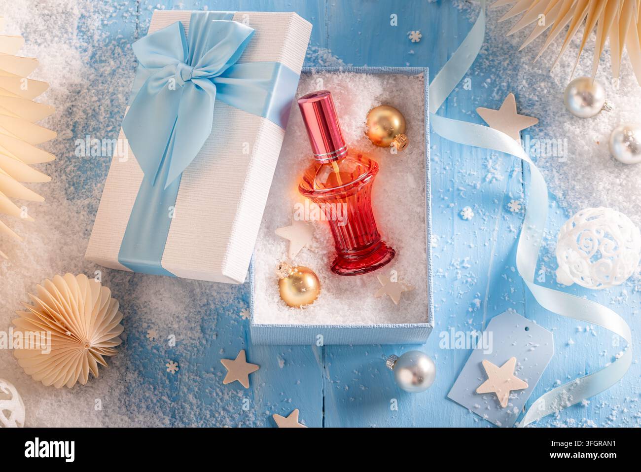 Elegante fiocco di raso blu che accentua una bottiglia di lusso. Dettaglio di un nodo di nastro fine che decora una confezione di fragranza per le festività stagionali. Foto Stock