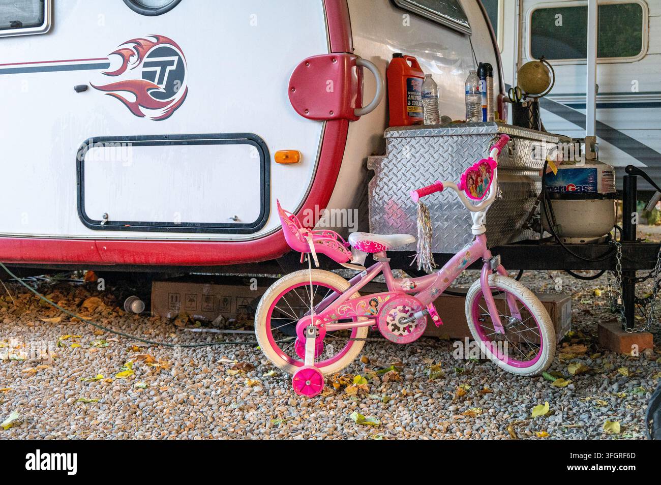 Una bicicletta per bambini parcheggiata fuori da una roulotte in una regione agricola rurale, che illustra la vita familiare dei lavoratori agricoli e le condizioni di alloggio. Foto Stock