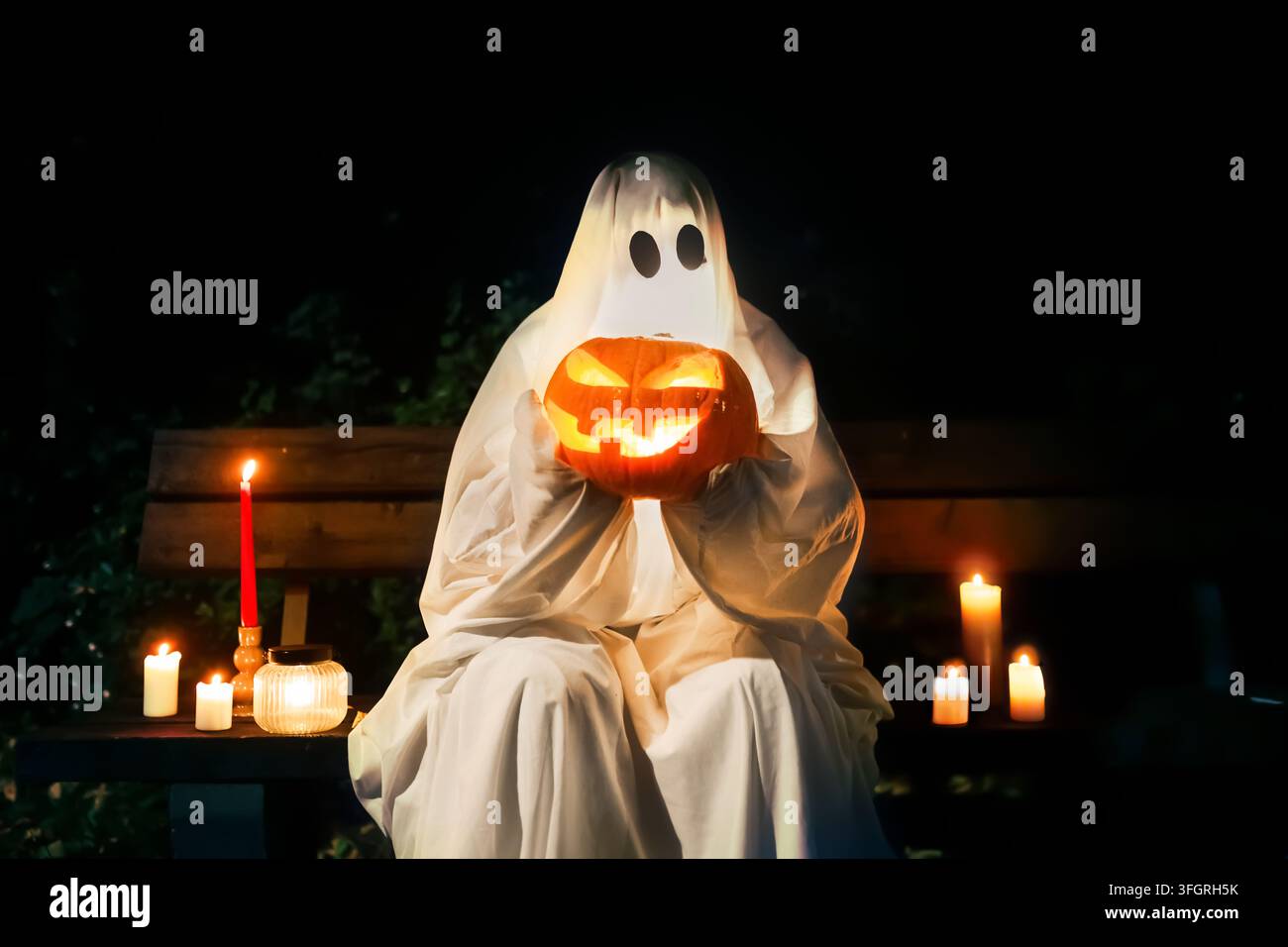 fantasma spaventoso che tiene una zucca luminosa nella notte buia. Una candela accesa aggiunge a questa celebrazione e tradizione di Halloween. Foto di alta qualità Foto Stock