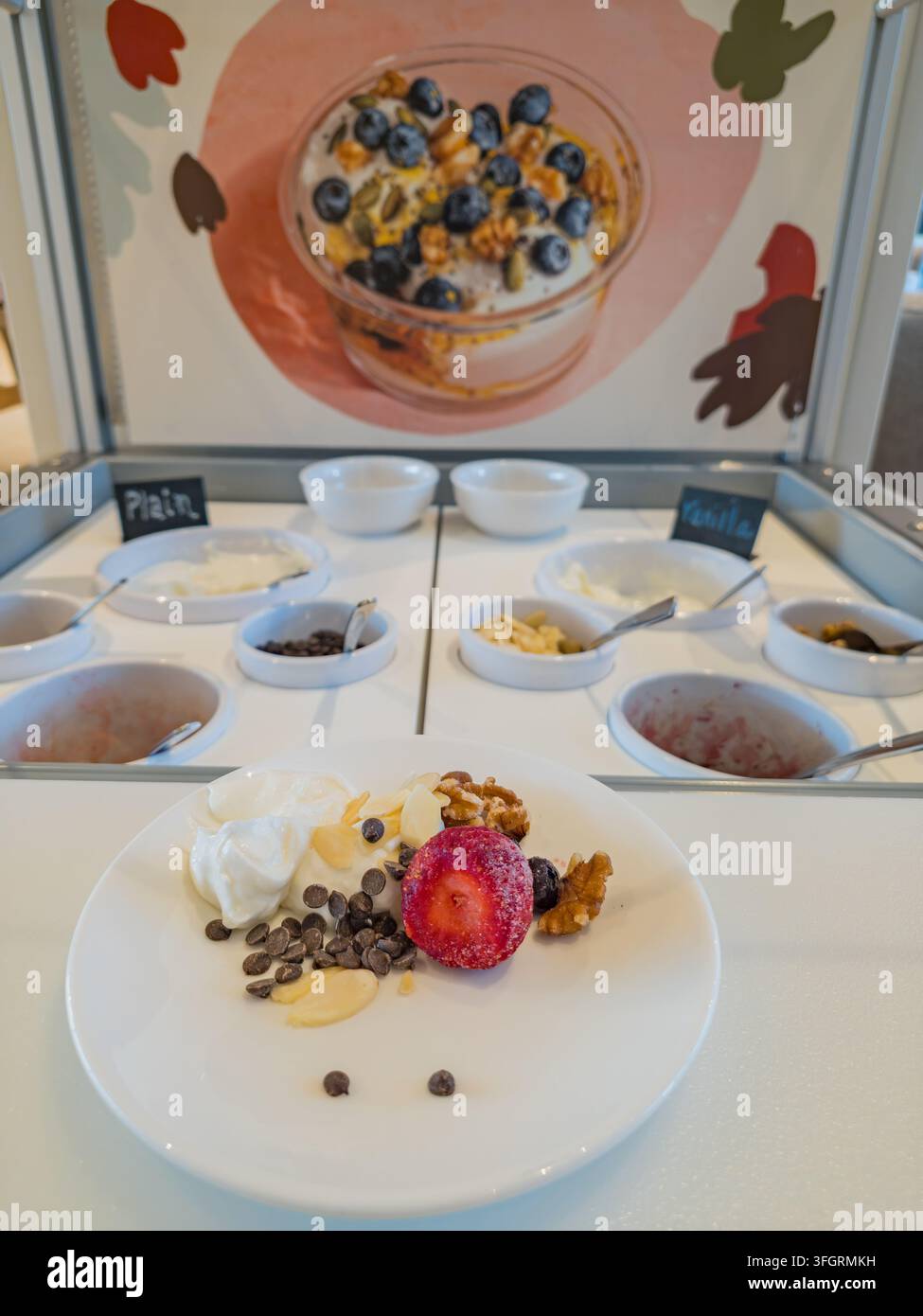Arkansas, Stati Uniti, 05 SET 2026 - Un piatto bianco contiene yogurt guarnito con fragole, noci, gocce di cioccolato e mandorle davanti a un Foto Stock
