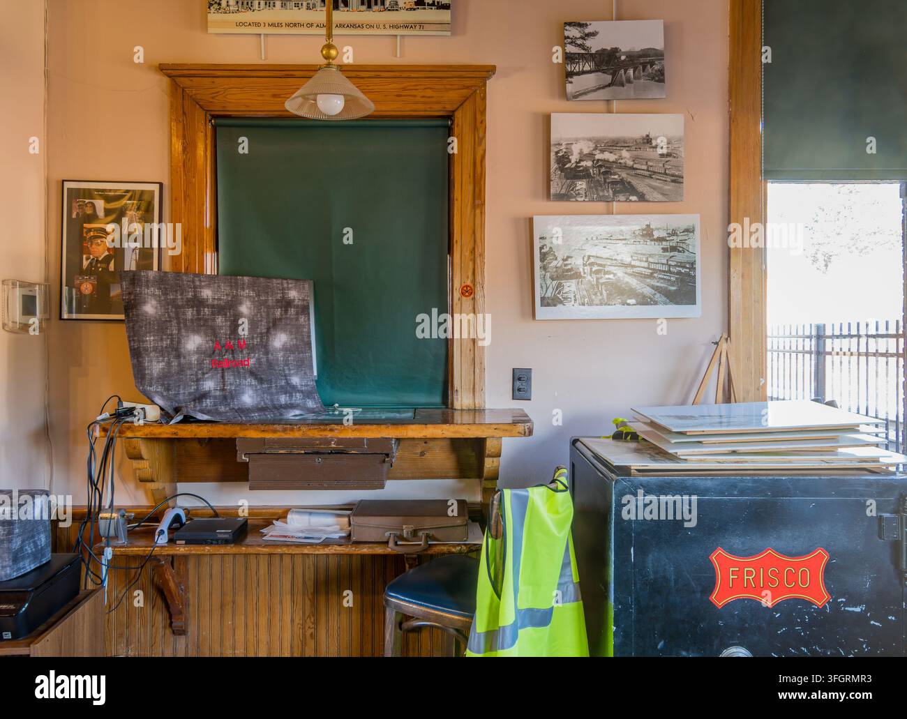Arkansas, Stati Uniti, 05 set 2026 – Scrivania in legno con computer e giubbotto di sicurezza è posizionata accanto a una cassaforte nera Frisco in una stanza decorata con vintage Foto Stock