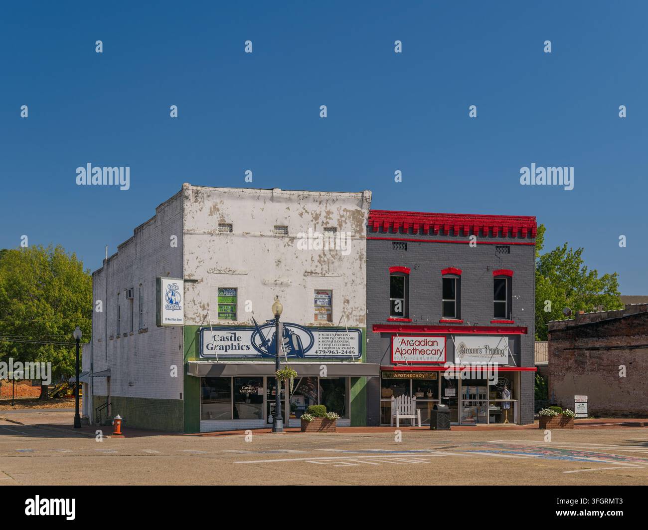 Arkansas, Stati Uniti, 05 SET 2026 - Una fila di edifici storici in mattoni con Castle Graphics e Arcadian Apothecary si trova in una strada soleggiata Foto Stock