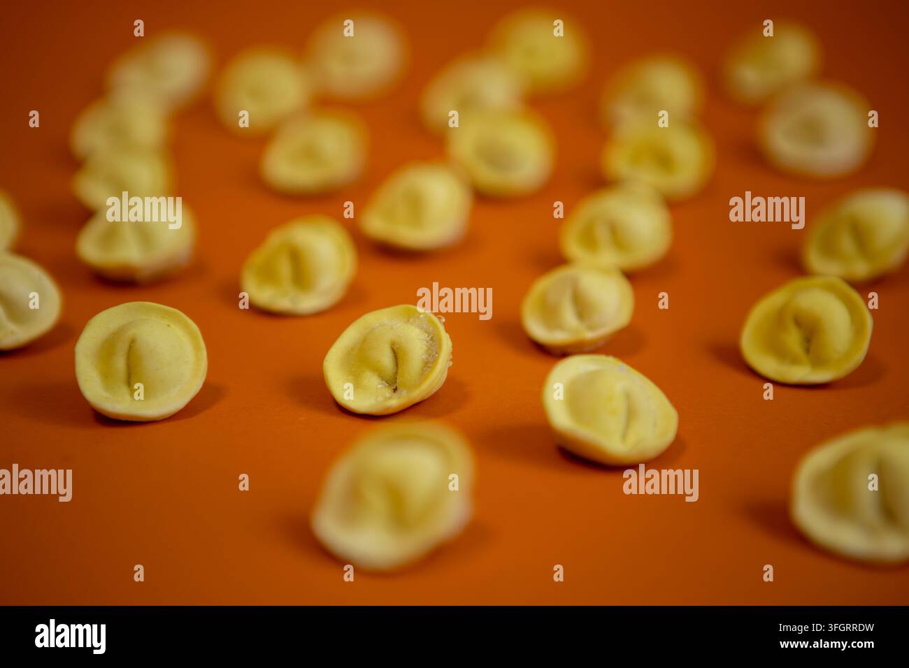 Gli gnocchi sono disposti su una superficie arancione in una cucina. Sono pronti per la cottura e mostrano la cura nella loro preparazione. Sono piccoli e Foto Stock