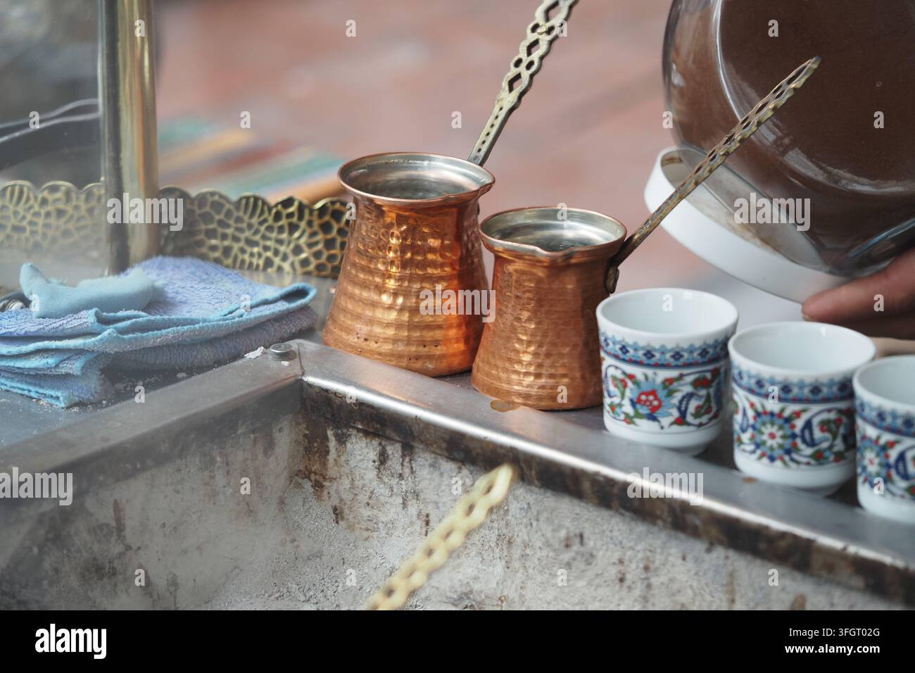 Caffettiere di rame e tazze decorative sono disposte su un banco di caffè Foto Stock
