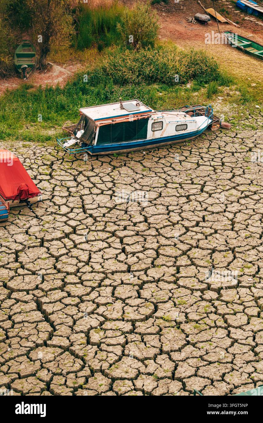 Piccole barche arenate su argilla secca e crepata a causa di livelli d'acqua estremamente bassi. Concetto di riscaldamento globale, grave crisi di siccità, impatto del cambiamento climatico, un Foto Stock
