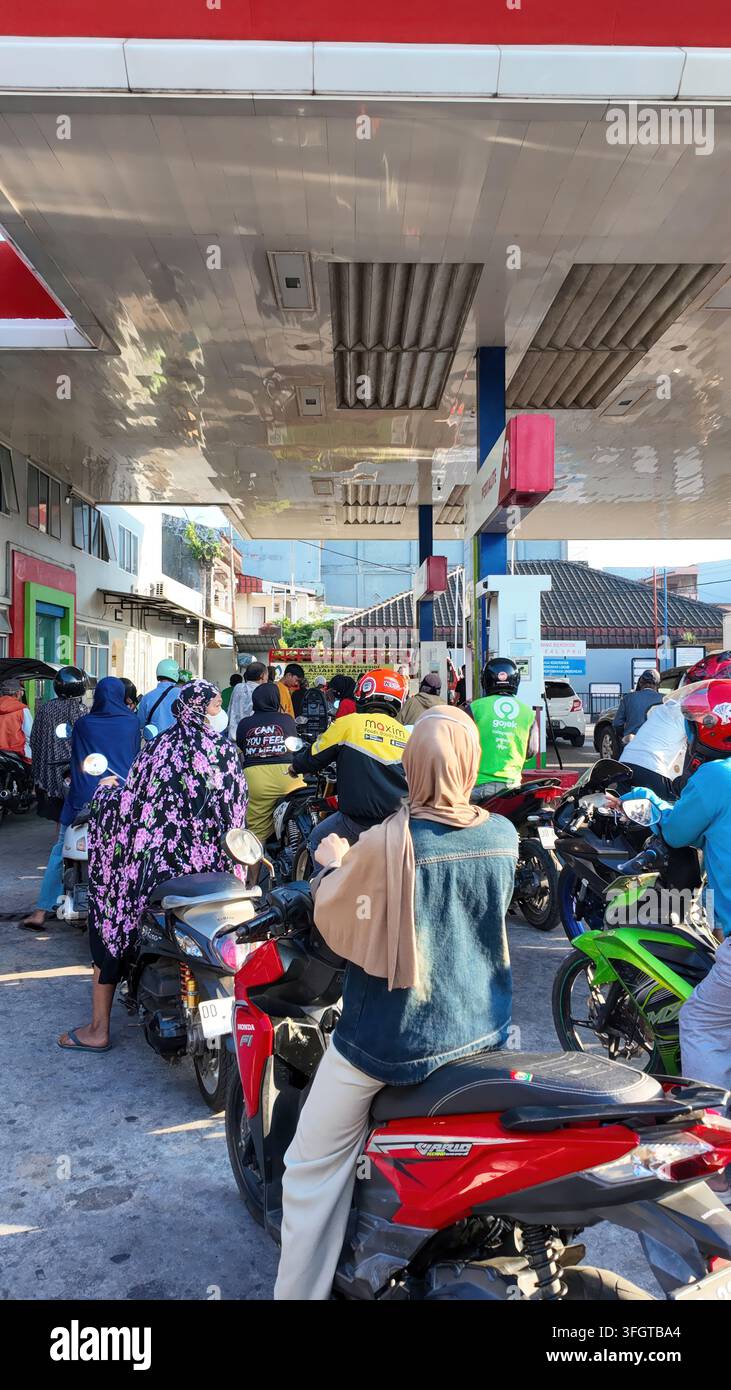 Vista verticale della folla di motociclisti in fila presso una stazione di servizio a causa di acquisti panici a Makassar Foto Stock