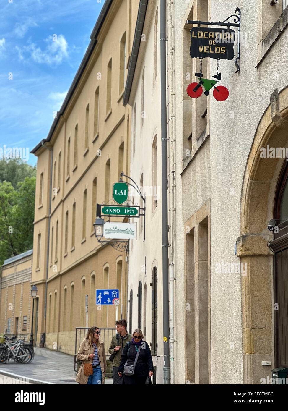 Facciata stradale europea con cartello di noleggio biciclette e pedoni che camminano. Strada europea classica fiancheggiata da edifici tradizionali beige con vint - Immagine stock catturata con smartphone