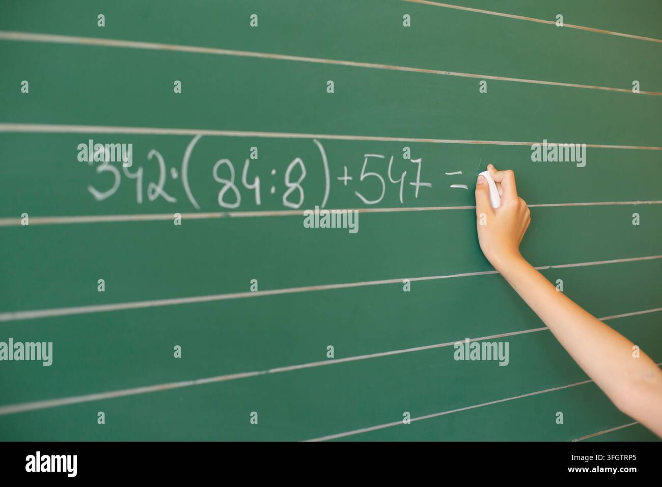 Uno studente pulisce la lavagna in un'aula scolastica durante una sessione di studio, preparandosi per le prossime lezioni e attività. Foto Stock
