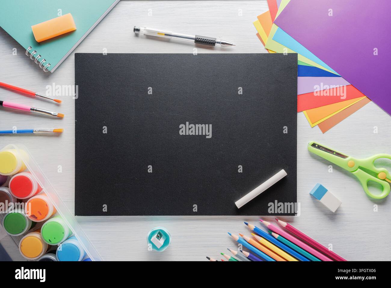 Materiali scolastici colorati intorno a una lavagna nera. Ritorno a scuola Foto Stock