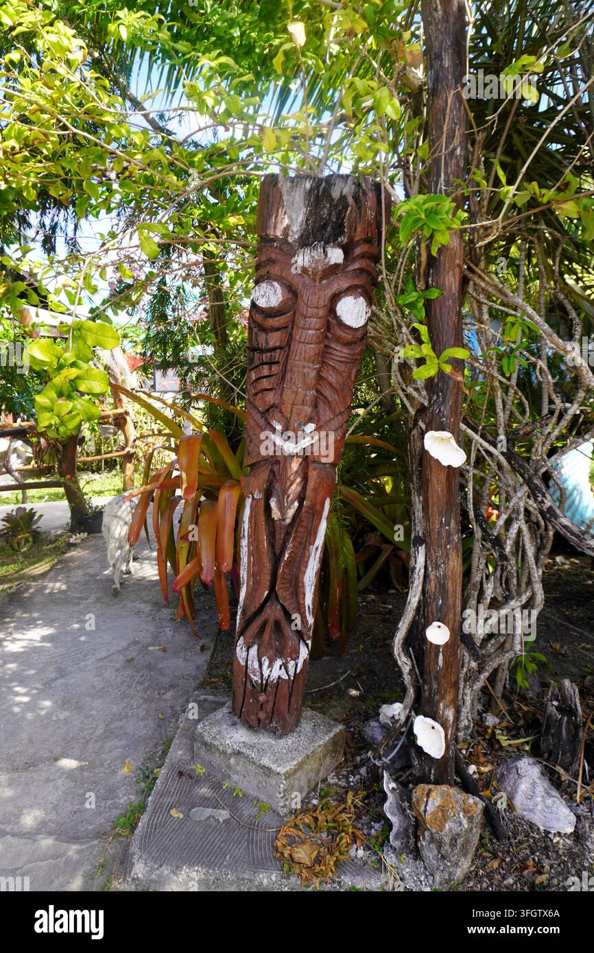 Maschera di palo totemico scolpita a mano in un ambiente tropicale Foto Stock