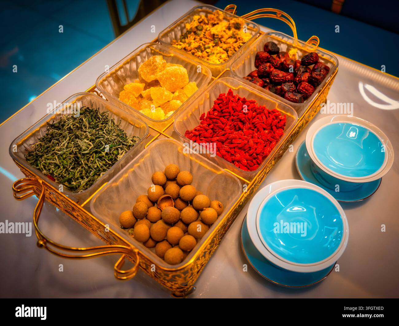 Set completo di ingredienti per il tè Sanpantai di un ristorante halal di Zhangye. Tè verde, goji, giuggiola rossa, longan, zucchero di roccia e crisantemo confezionati in oro Foto Stock