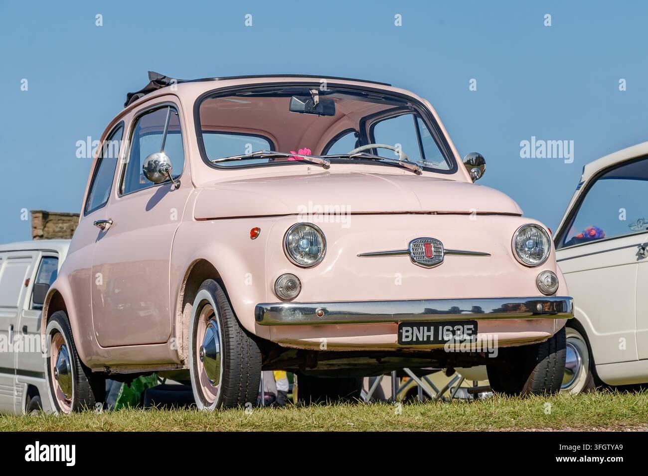 Auto Fiat 500 rosa parcheggiata in mostra all'aperto Foto Stock