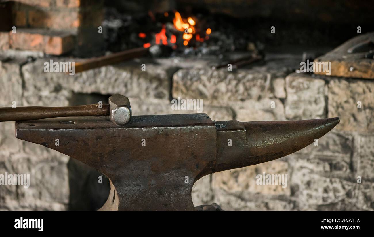 Il martello giace sull'incudine in una vecchia fucina. Antica arte artigiana Foto Stock