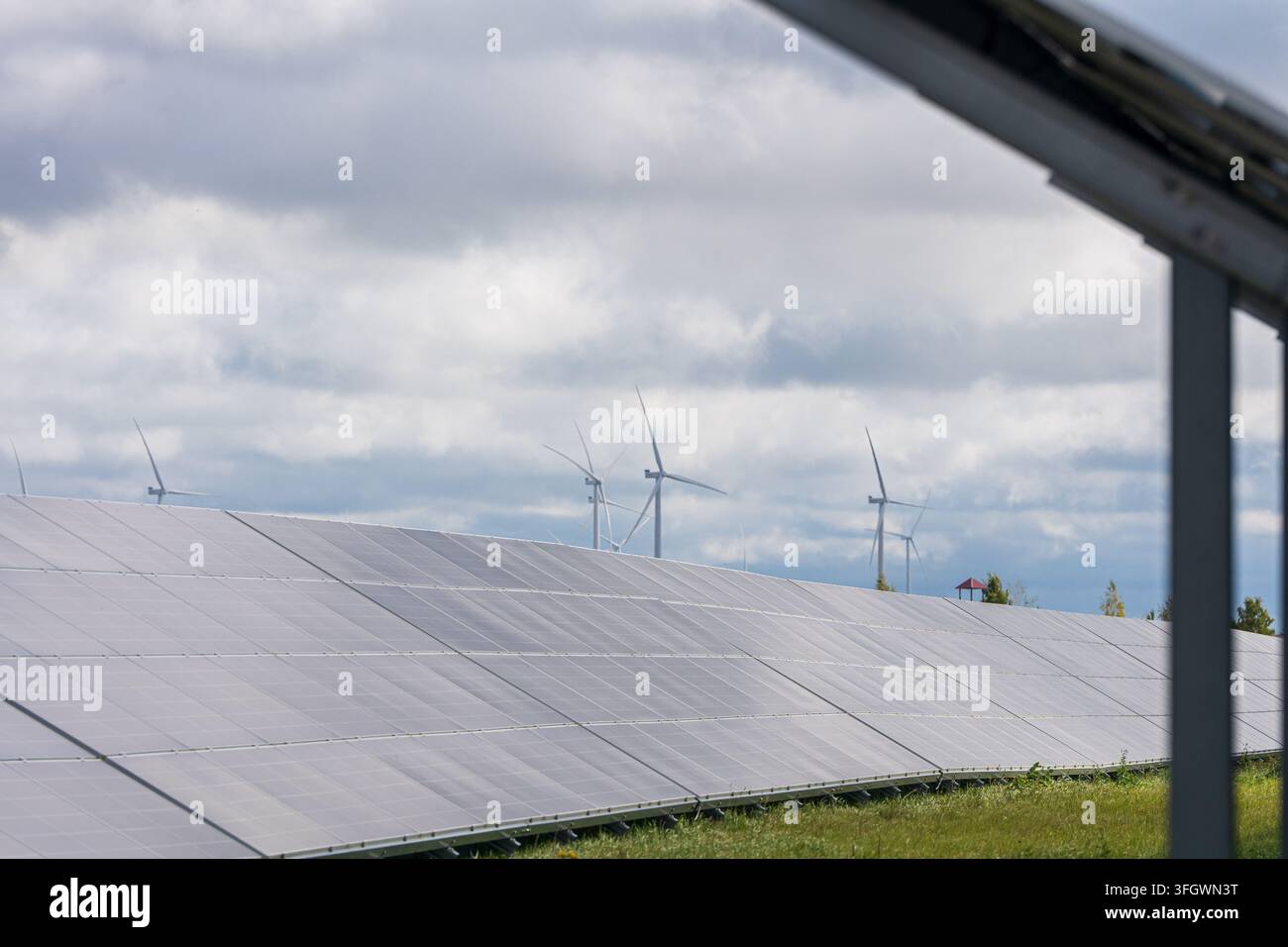 Pannelli solari e turbine eoliche in un campo verde sotto un cielo nuvoloso . Foto di alta qualità Foto Stock