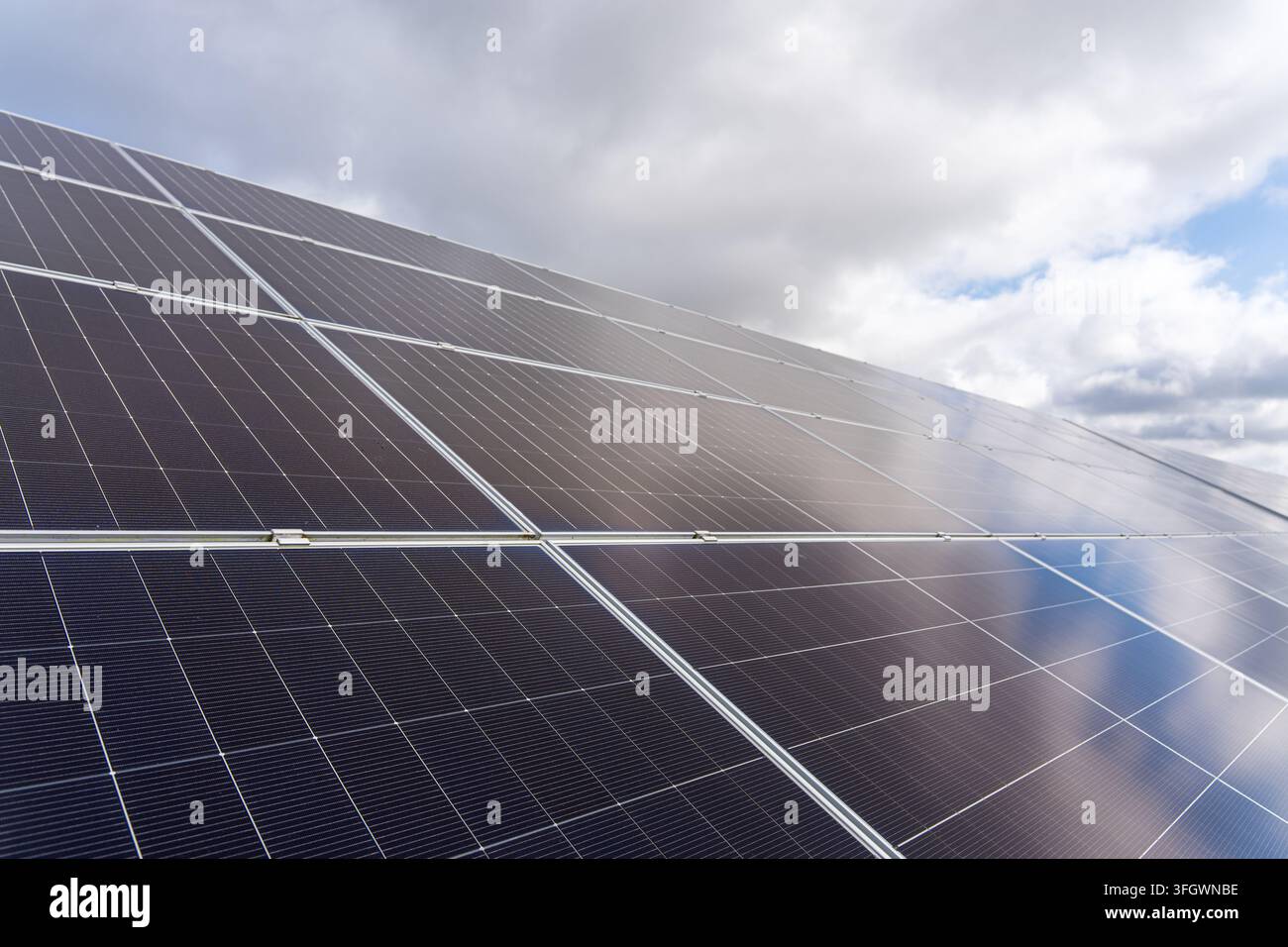 Array di pannelli solari che riflette le nuvole sotto un cielo parzialmente nuvoloso . Foto di alta qualità Foto Stock