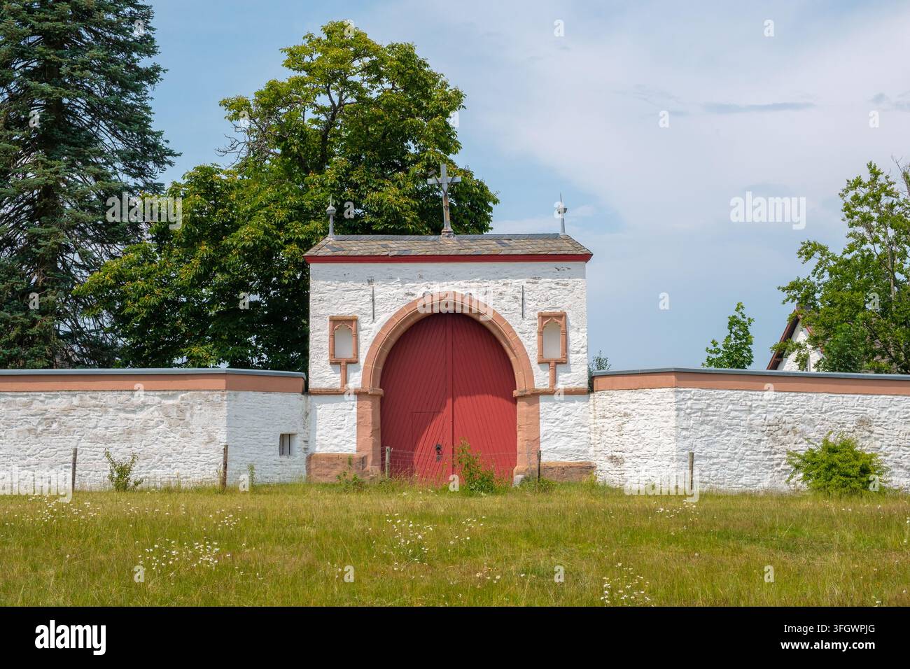 Muro bianco del monastero con cancello d'ingresso rosso all'abbazia di Mariawald nell'Eifel, Germania Foto Stock