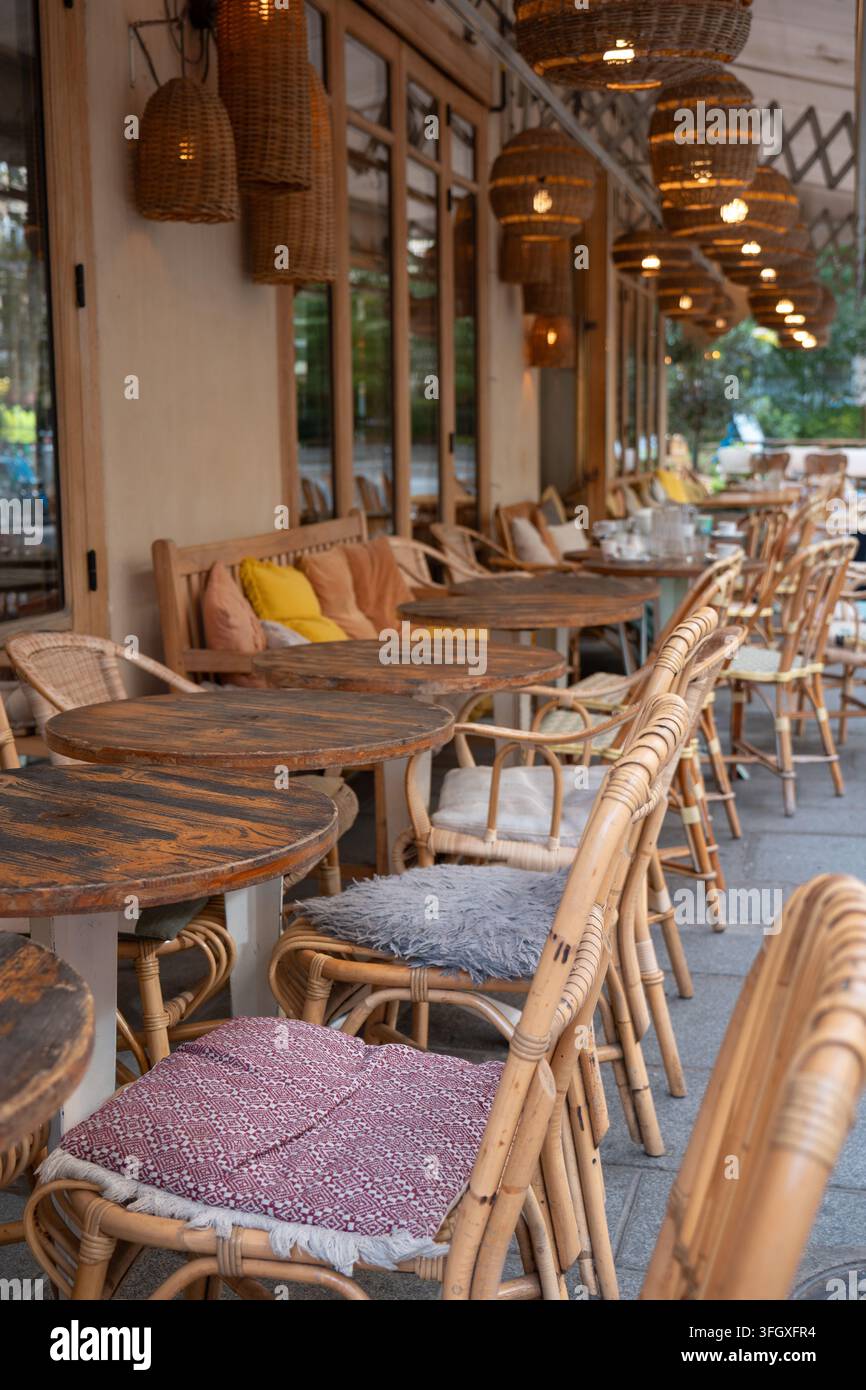 Terrazza di bistrot parigino con sedie affascinanti in rattan, cuscini fantasia e un'atmosfera accogliente per un'esperienza di cena all'aperto Foto Stock