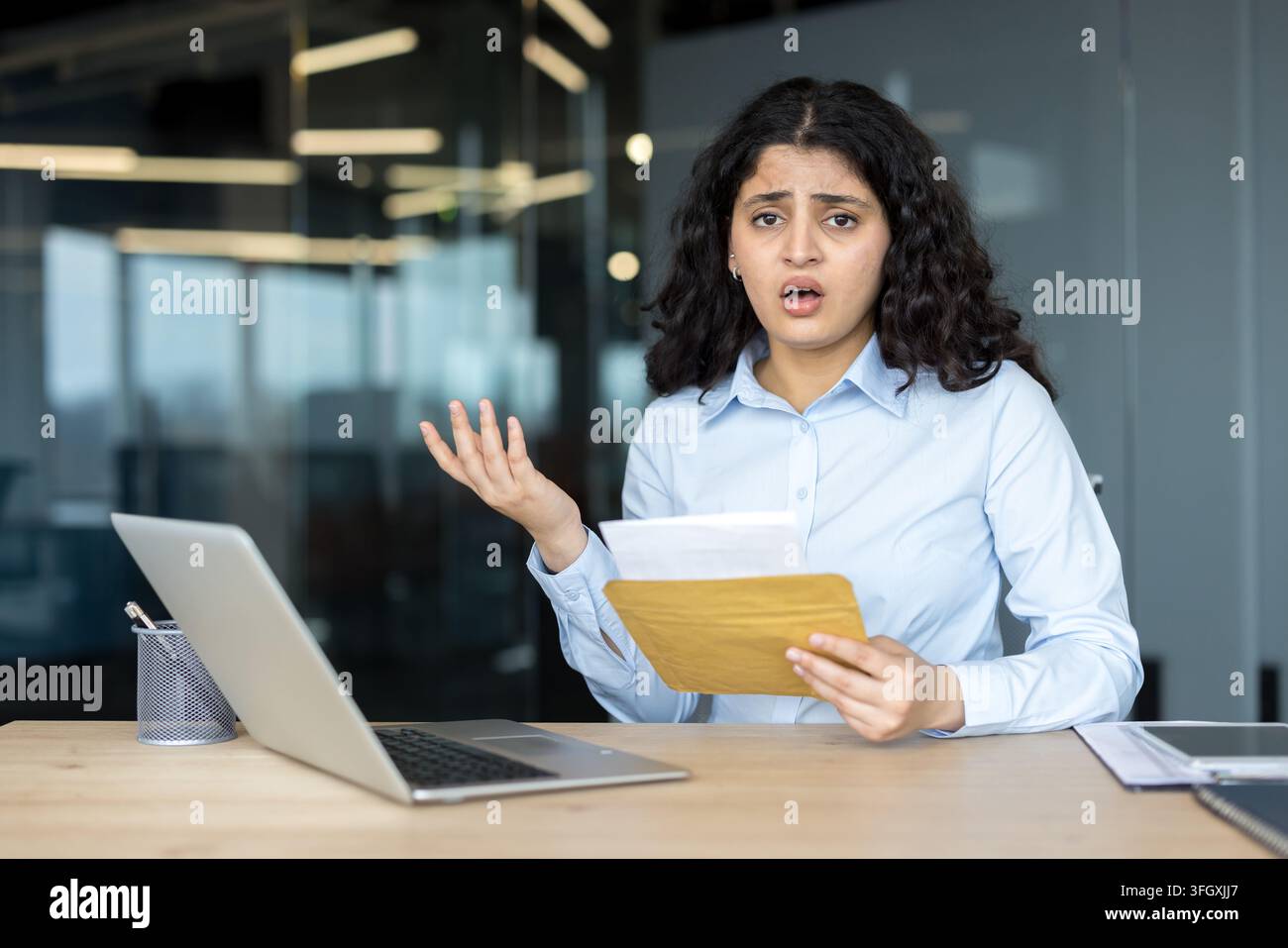 Donna d'affari stressata con laptop e documenti in ufficio. Foto Stock