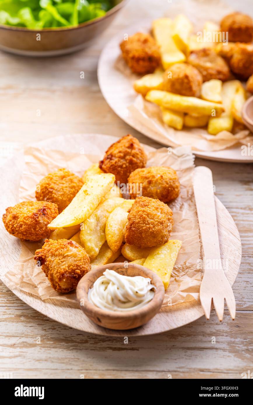 Deliziosi fish and chips serviti con salsa tartara e insalata verde fresca Foto Stock