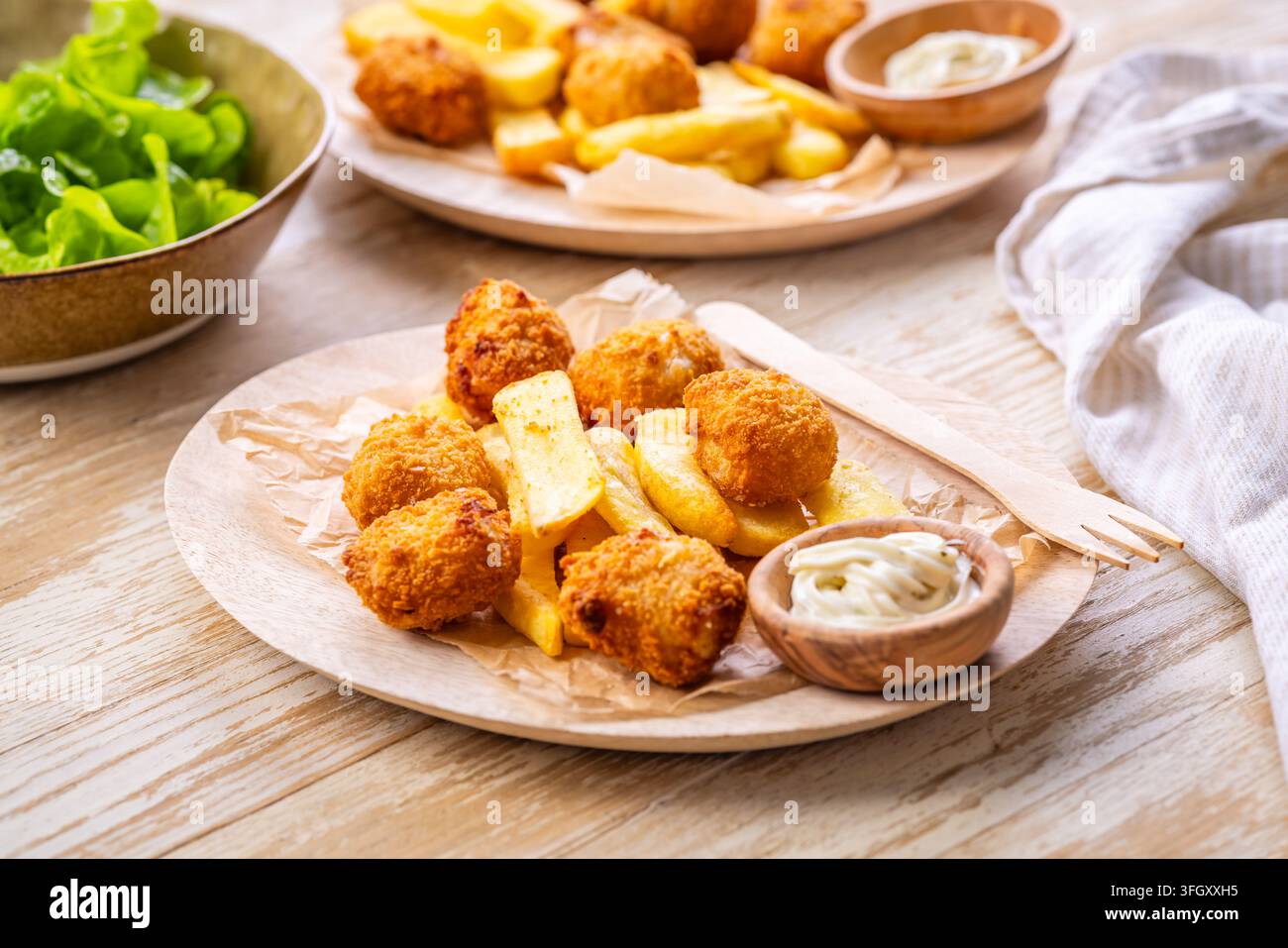 Deliziosi fish and chips serviti con salsa tartara e insalata verde fresca Foto Stock