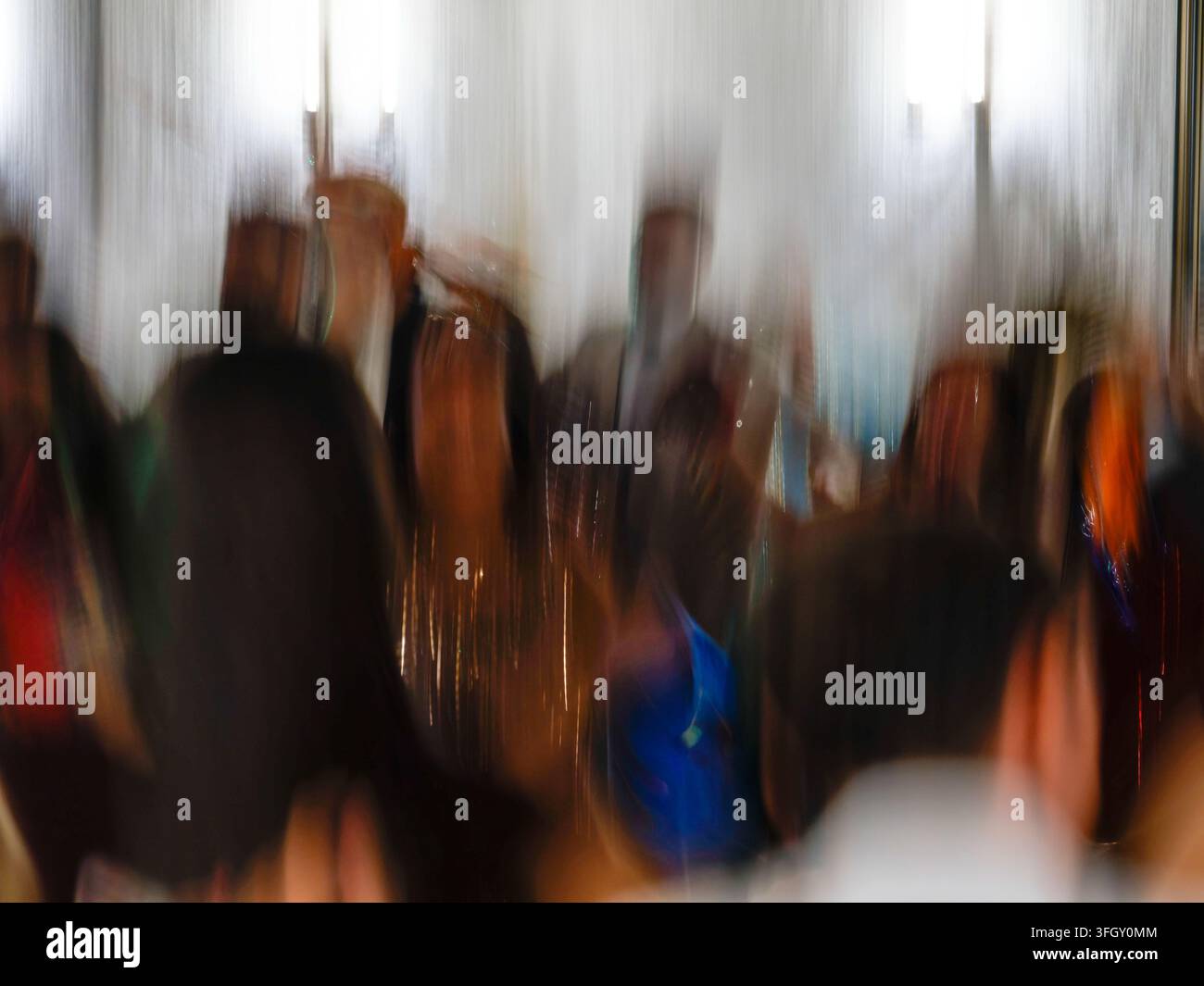 Folsa astratta sfocata di persone a un evento indoor con movimento della fotocamera intenzionale Foto Stock