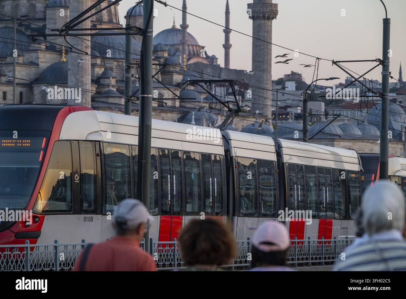 Vista di un tram moderno che passa davanti alla storica moschea di Suleymaniye durante l'ora dorata a Istanbul, Istanbul, Turkiye. Foto Stock