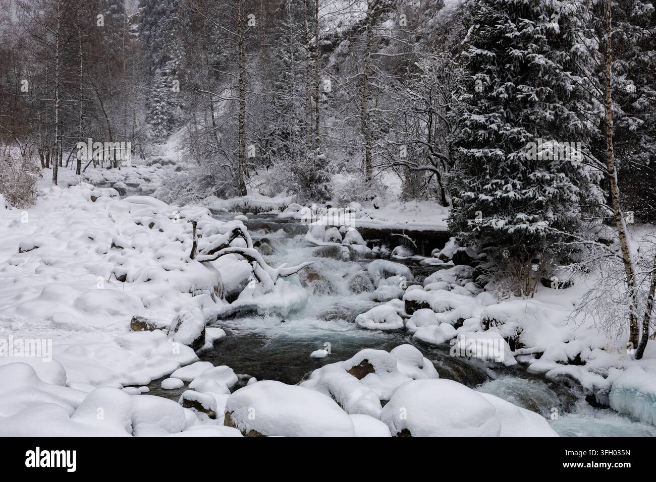 Fiume invernale che scorre oltre rocce coperte di neve, Kazakistan Foto Stock