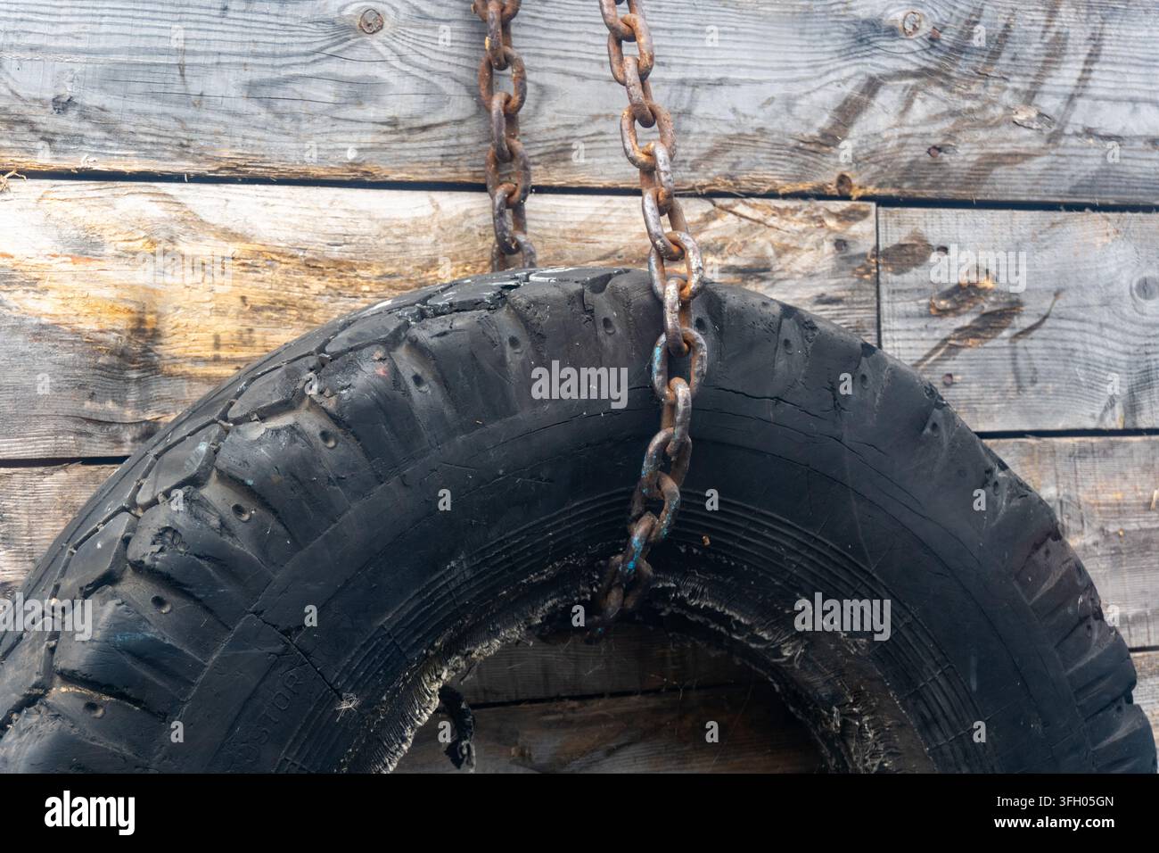 Vecchio pneumatico di gomma appeso a una catena come paraurti per il molo delle barche Foto Stock