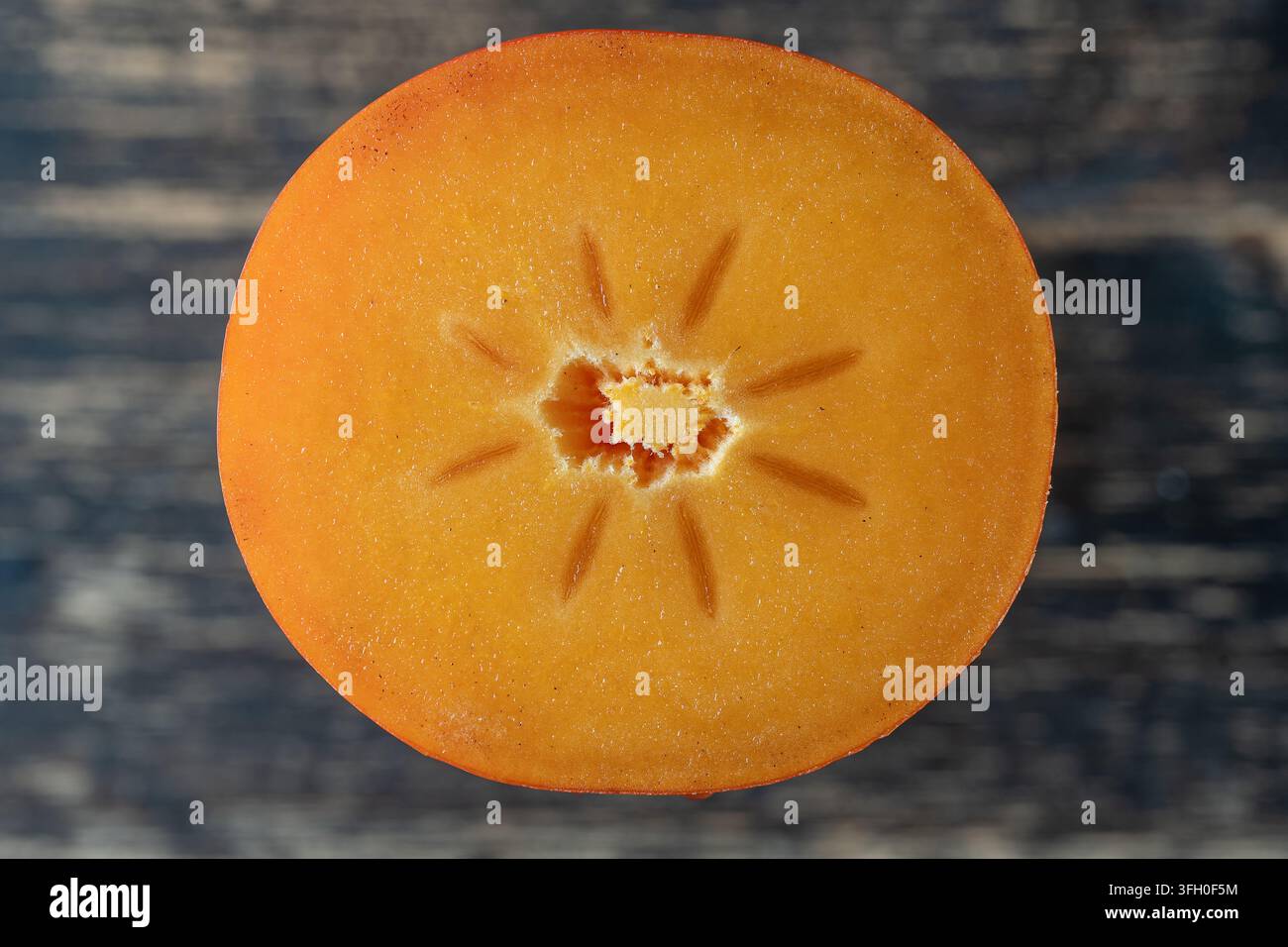 Persimmon arancio, tagliato a metà con la consistenza di semi e polpa. Primo piano delle sezioni di permimon, vista dall'alto, macro Foto Stock