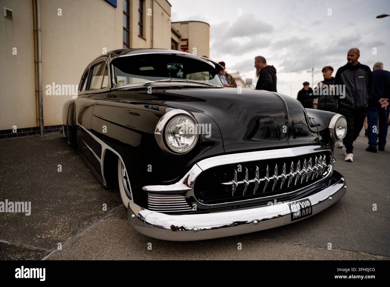 Hot rod nera lucida alla Race to the Waves 2026, Bridlington South Beach, East Yorkshire, folle che ammirano l'auto americana classica Foto Stock