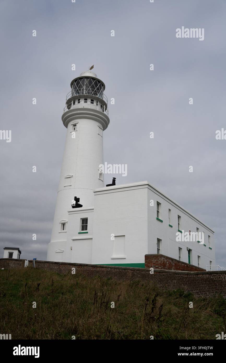 Faro di Flamborough Head, East Yorkshire, una torre bianca impressionante che si erge sopra il suo cottage del guardiano sotto un cielo nuvoloso Foto Stock