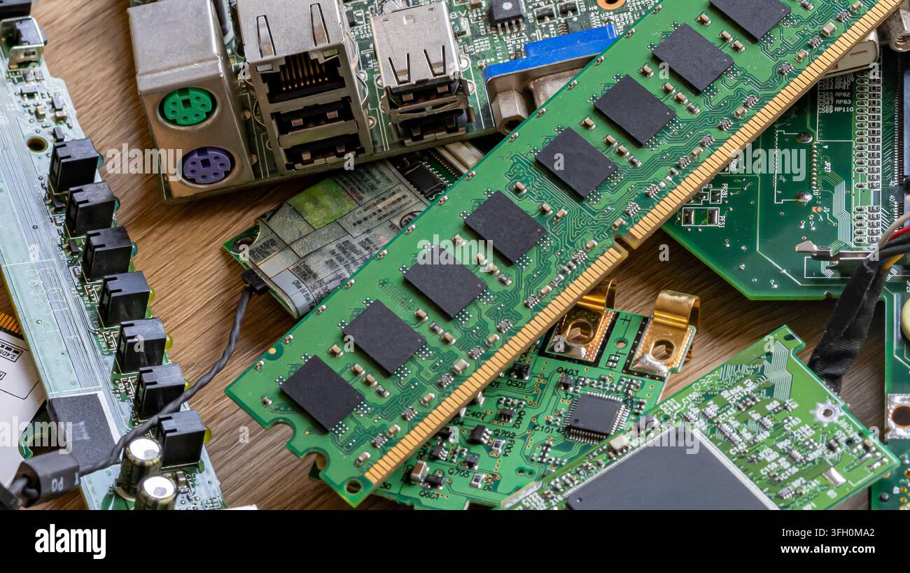 Una pila di varie schede elettroniche, modulo di memoria RAM e componenti informatici disposti su un tavolo di legno. Concetto per rifiuti elettronici, aggiornamento dell'hardware Foto Stock