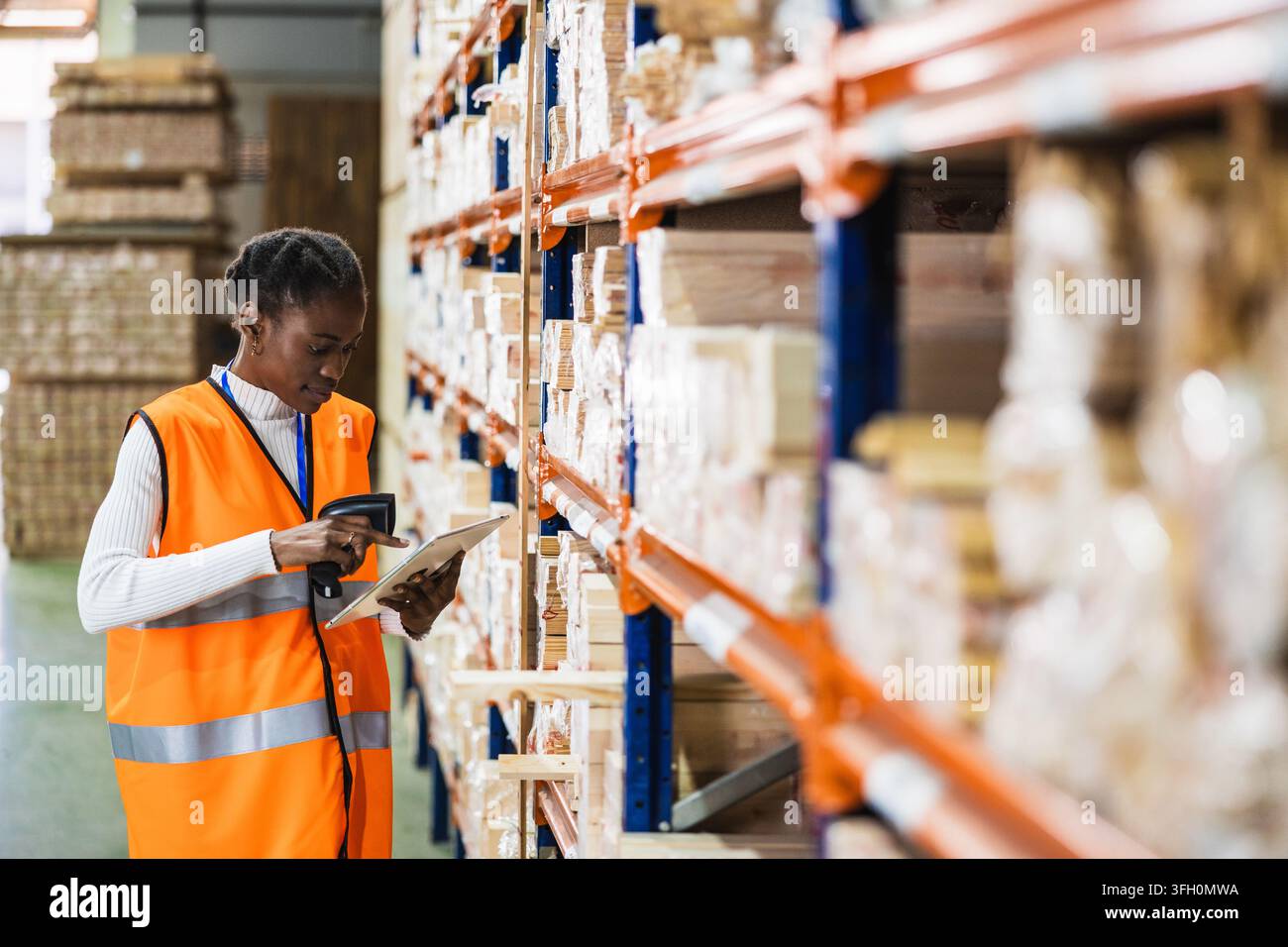 Lavoratrice che scansiona l'inventario in un magazzino di segheria Foto Stock