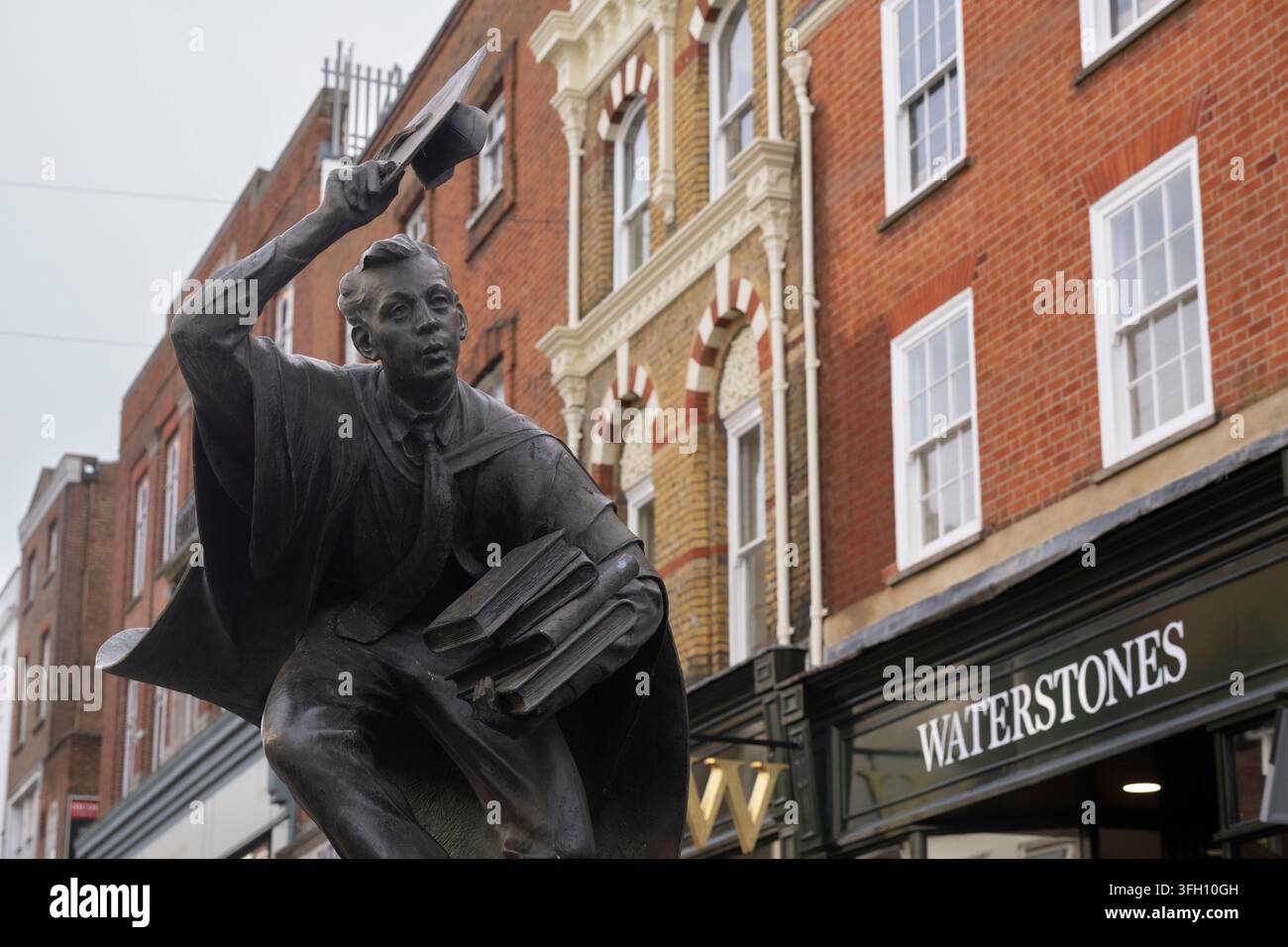 Una statua di studioso in bronzo sfreccia davanti a Waterstones a Guildford Foto Stock