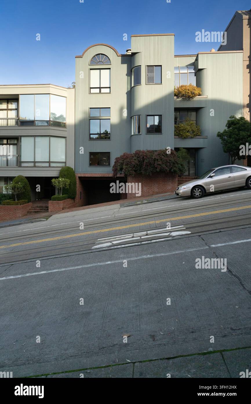 Un'auto parcheggia su una ripida collina di San Francisco vicino a Lombard Street, mostrando i famosi dislivelli e i binari del tram della città. Foto Stock
