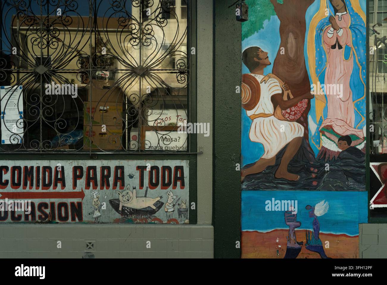 Nel quartiere Mission di San Francisco, un chiosco gastronomico presenta vivaci murales della Madonna di Guadalupe per celebrare la cultura e vendere cibo tradizionale. Foto Stock