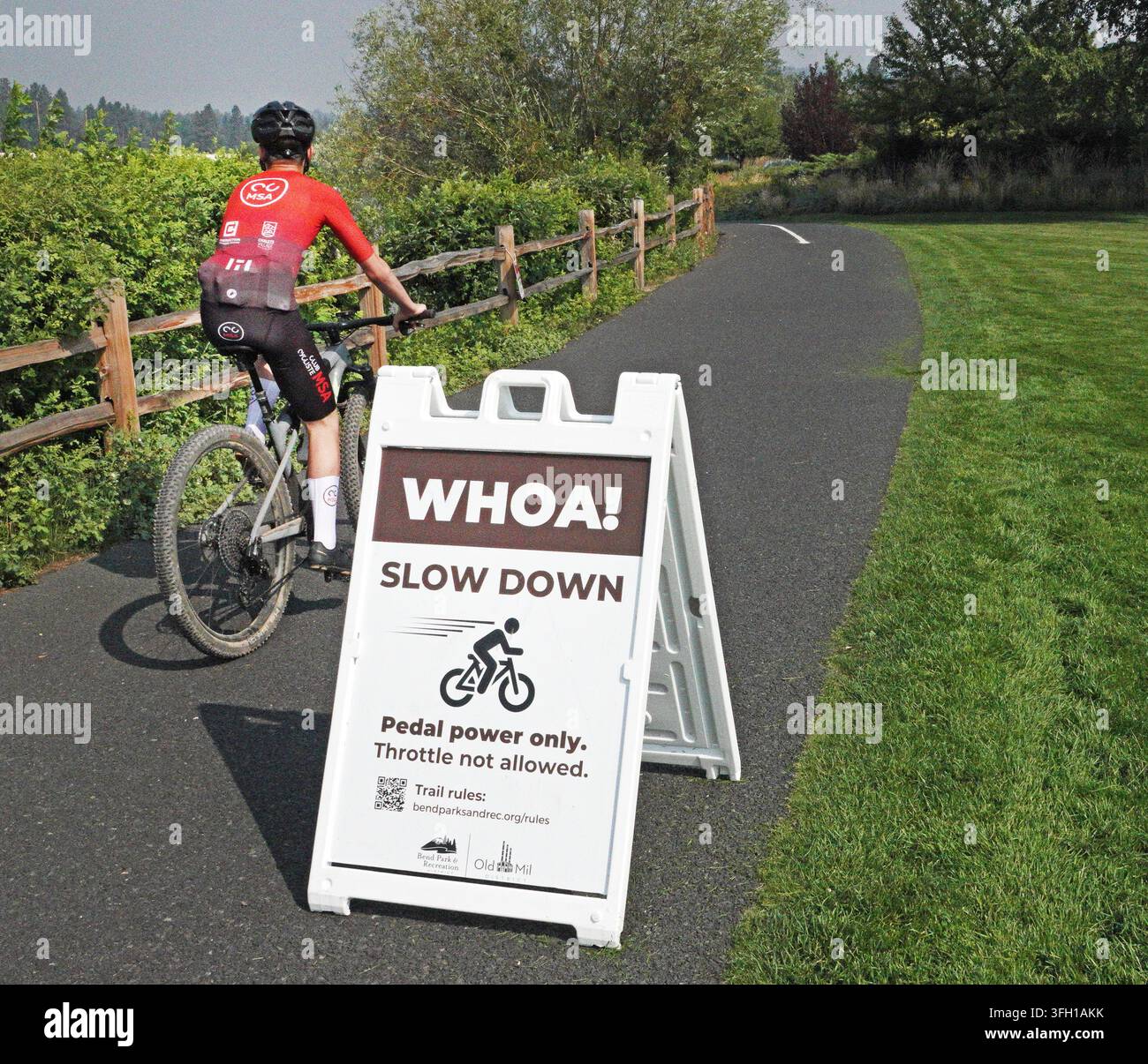 Un cartello che avverte i ciclisti di rallentare e che le biciclette elettriche sono ora ammesse sul percorso ciclabile lungo il fiume Deschutes a Bend, Oregon. Foto Stock