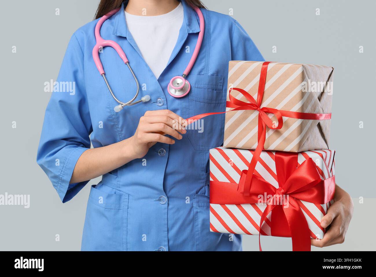 Apprezzamento sanitario e riconoscimento del personale medico, infermiera che tiene scatole regalo con nastri rossi per bonus festivo o programma di ricompensa del personale ospedaliero Foto Stock